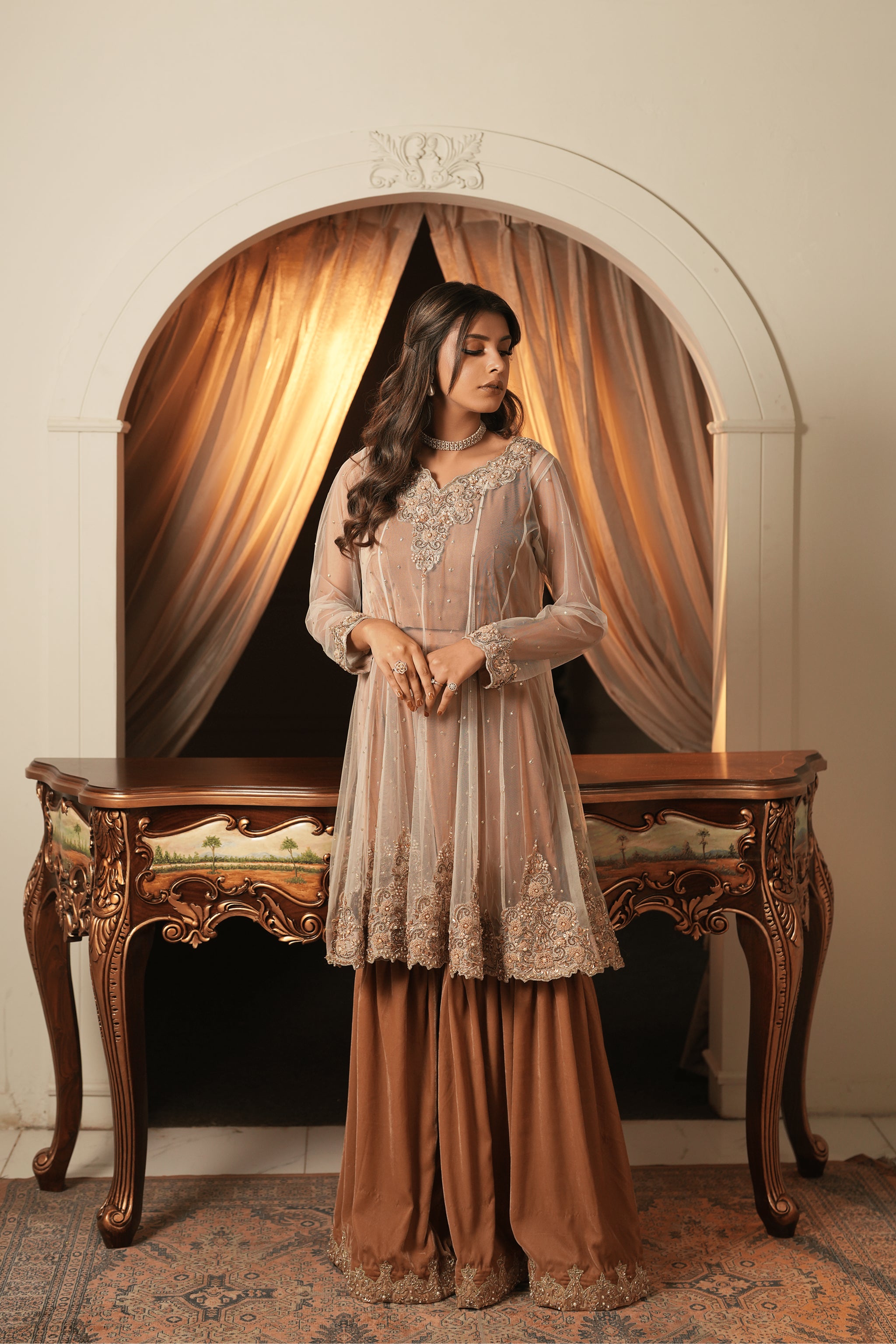 Front view of a copper and rust brown bridal wear ensemble in net and velvet, short Anarkali-style shirt with silver